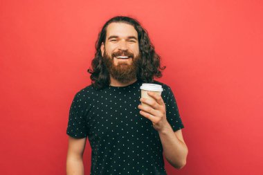 A photo of a man happily holding a cup of coffee while smiling at the camera