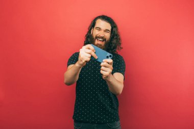 A picture of young man  playing games in his new phone him being very excited