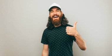 A bearded man is cheerfuly holding a thumb up for approval