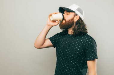 A man enjoying his delivered coffee near a grey wall