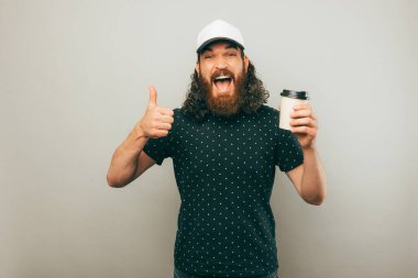  A delivery man holding a cup of coffee and showing a thumb up