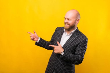 An excited business man is pointing with his both hands at a free space while smiling