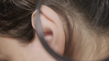 Close up footage of doctor investigating woman patient ear with magnifying glass.