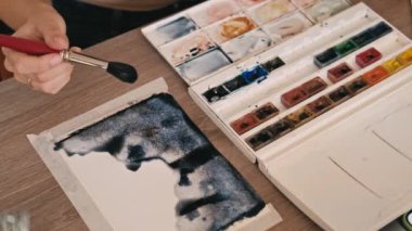 Close up video of woman painting with watercolors.