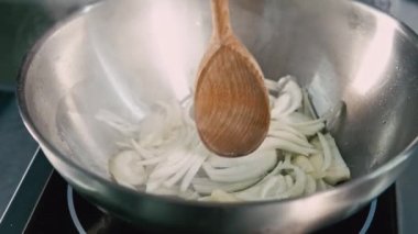 close up video of chef preparing onion in frying pan.