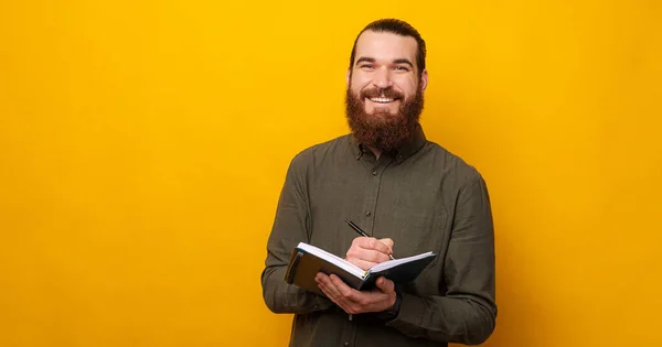 Content Bearded Man Smiles Camera While Holding Planner Pen Studio — Stockfoto