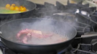 Aşçı ahtapotu şarap ve alevle kızartma tavasında hazırlıyor..