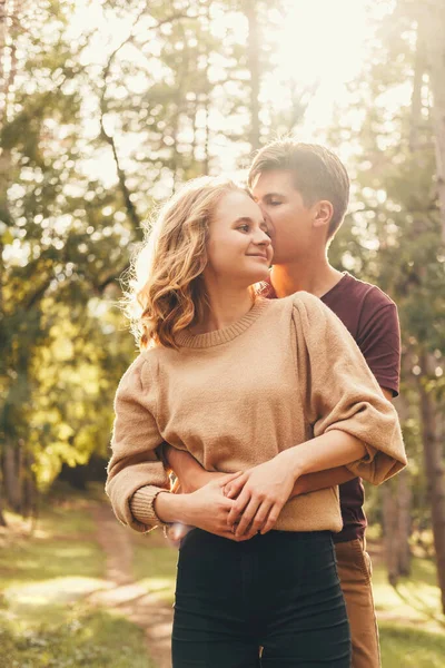 公園で一緒に時間を過ごすかわいい若いカップルの垂直ショット 男は女を抱きかかえている — ストック写真