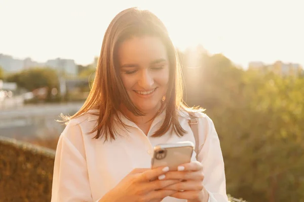 Jovem Mulher Sorrindo Está Digitando Uma Mensagem Seu Telefone Livre — Fotografia de Stock