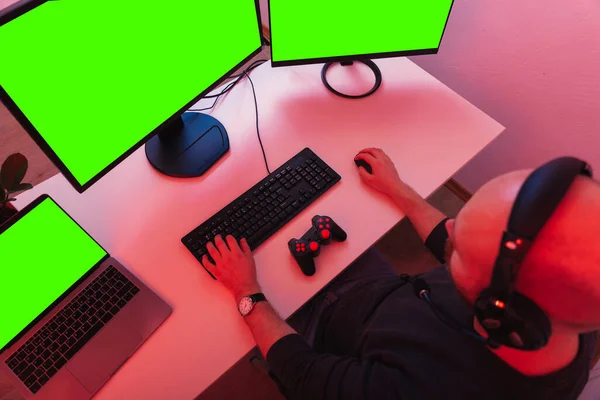 大胆な男が座っていると3つの緑の画面のコンピュータの前で再生されます 赤い光で撃たれた — ストック写真