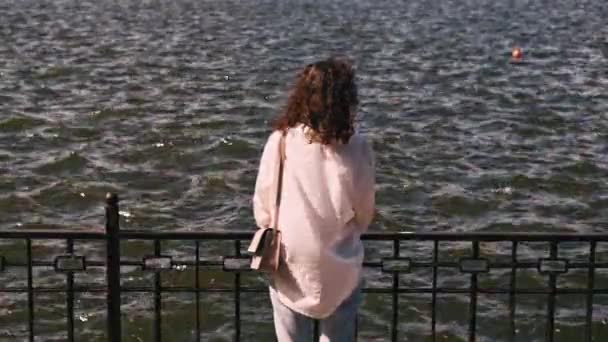 수없는 여자가 쉬면서 공원에서 호수의 파도를 바라보는 — 비디오