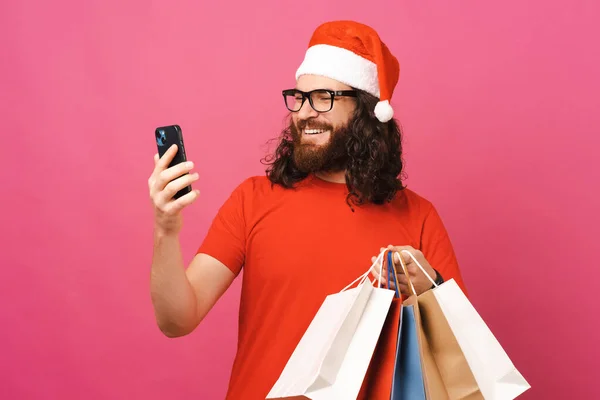 Homem Extático Chapéu Natal Está Comprando Telefone Enquanto Segurando Alguns — Fotografia de Stock