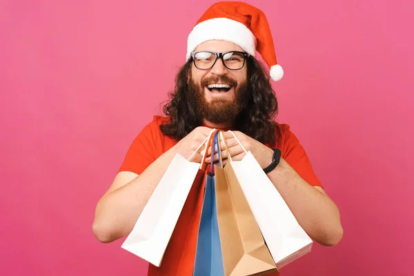 Curly Człowiek Okularach Boże Narodzenie Kapelusz Trzyma Kilka Toreb Zakupy — Zdjęcie stockowe