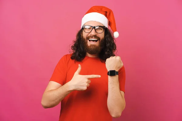 크리스마스 모자쓰고 시계를 대머리 남자가 분홍색 스튜디오에서이걸가르키고 있습니다 — 스톡 사진