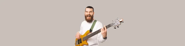 배너는 수염을 남자가 베이스 기타를 연주하는 모습을 찍었다 스튜디오 라이트 — 스톡 사진