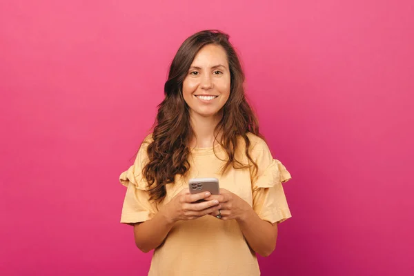 Jovem Encantadora Com Cabelos Longos Sobre Backogrund Rosa Segurando Smartphone — Fotografia de Stock