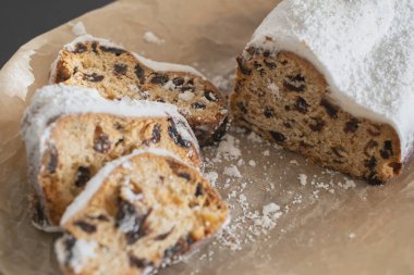 Geleneksel Noel arkaplanda mumlarla süslenmiş kurutulmuş meyve ve fındıklardan yapılmış pudra şekeri serpiştirilmiş. Geleneksel Noel keki.