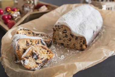 Geleneksel Noel arkaplanda mumlarla süslenmiş kurutulmuş meyve ve fındıklardan yapılmış pudra şekeri serpiştirilmiş. Geleneksel Noel keki.