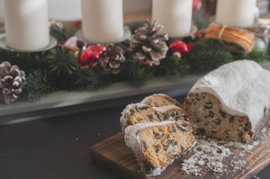 Geleneksel Noel arkaplanda mumlarla süslenmiş kurutulmuş meyve ve fındıklardan yapılmış pudra şekeri serpiştirilmiş. Geleneksel Noel keki.