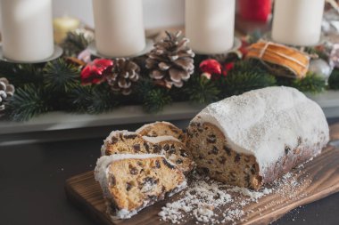 Geleneksel Noel arkaplanda mumlarla süslenmiş kurutulmuş meyve ve fındıklardan yapılmış pudra şekeri serpiştirilmiş. Geleneksel Noel keki.