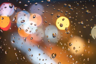 Mavi cam arka planda yağmur damlaları. Sokak bokeh 'i bulanıklaştı. soyut arkaplan