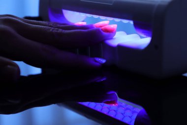 Fotoğrafçılık polarize ultraviyole lamba ile manikür yapıyor.