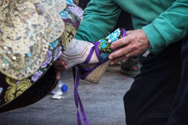 Bir kadın sandalyede oturuyor ve elinde bir iplik tutuyor.