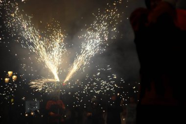 Kırmızı üniformalı mutlu genç bir kadının karanlık gökyüzünde bir maytap tuttuğunu gördüm.