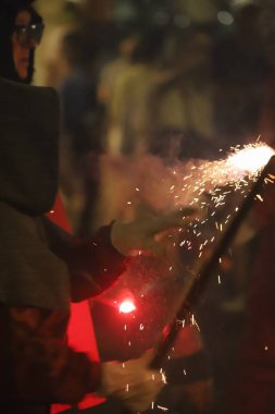 close up of a happy young woman in a red uniform holding a sparklers in the dark sky