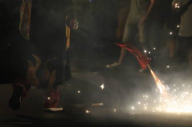close up of a happy young woman in a red uniform holding a sparklers in the dark sky