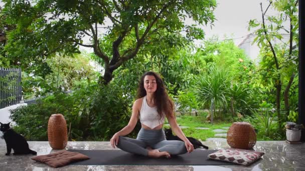 Frau macht Yoga in Lotus-Position gegen üppiges Grün — Stockvideo