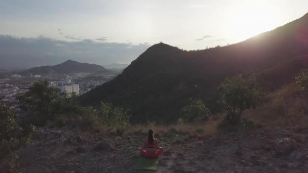 日出日落时，女人在荷花中与山相对立，享受瑜伽 — 图库视频影像