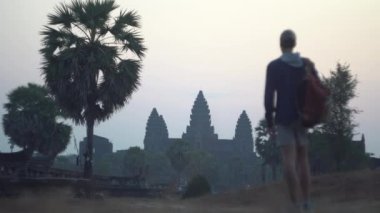 Sırt çantalı genç adam, Angkor Wat Tapınağı 'nın muhteşem eski sarayının tadını çıkarıyor.