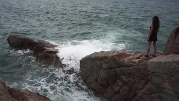 Lady si erge su una grande roccia guardando meravigliose onde del mare — Video Stock