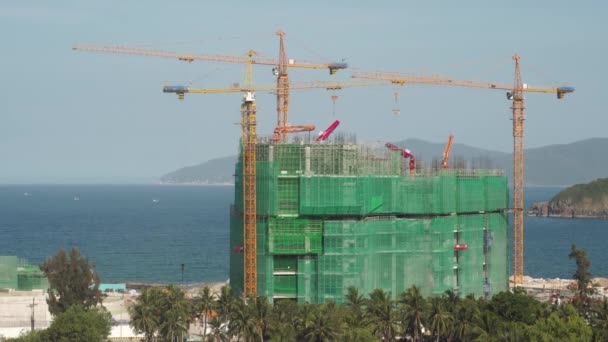 Site de construction d'hôtel avec grues à tour sur la côte maritime — Video