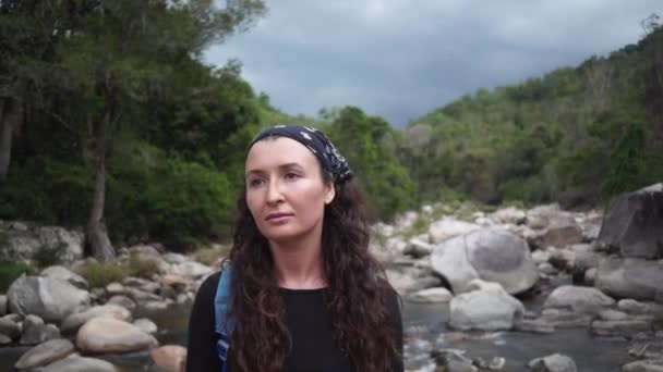 Dame pose regardant dans la caméra contre les rochers de rivière de montagne — Video