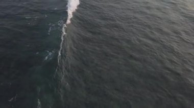 Büyük mavi okyanus dalgaları yoğun beyaz köpükle yuvarlanır.