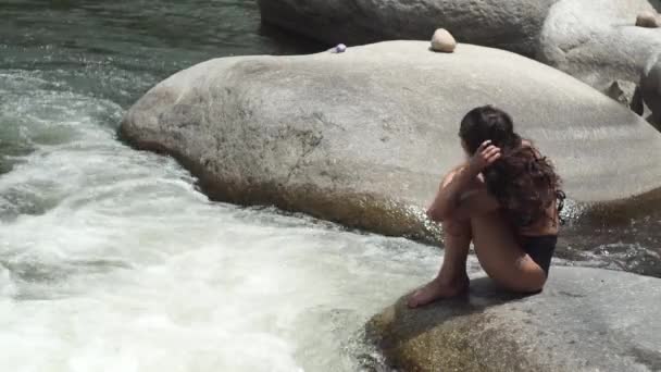 Dame aux cheveux bouclés en bikini lave visage avec de l'eau de rivière — Video