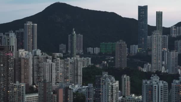 Grandi edifici della città con luci nelle finestre contro la collina a Hong Kong — Video Stock
