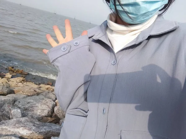 a woman in a protective mask and a scarf on the beach