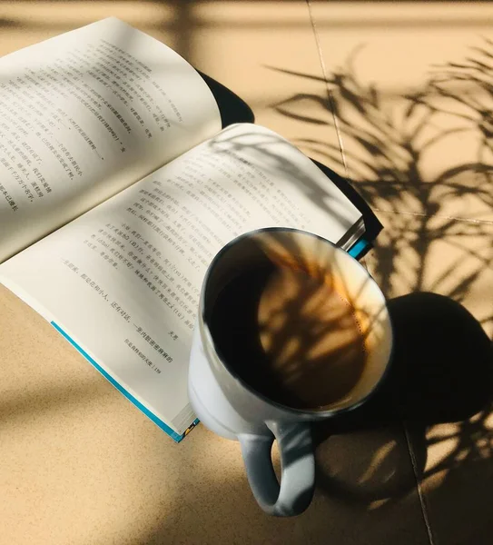 book with a cup of coffee and a pen on a wooden table