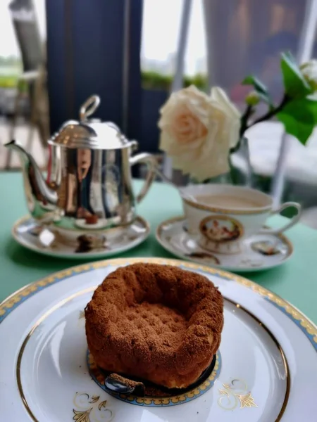 a cup of tea with a cake on a white plate