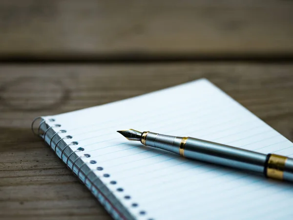 notebook and pen on wooden background