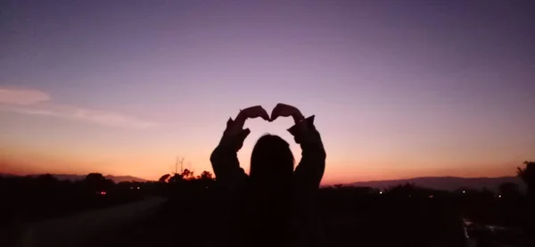 silhouette of a man with a heart on the background of the sunset