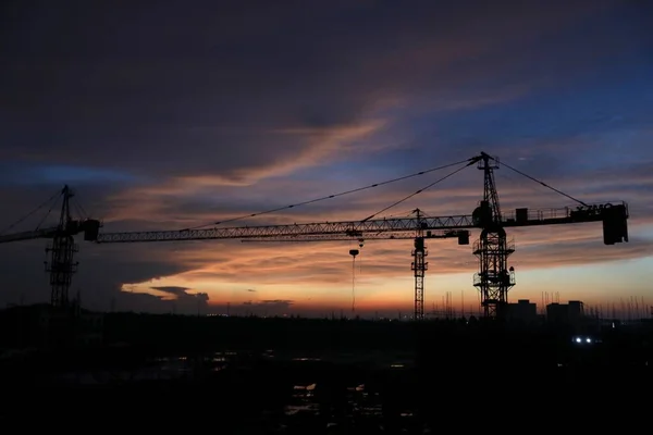 silhouette of a construction crane on a background of sunset