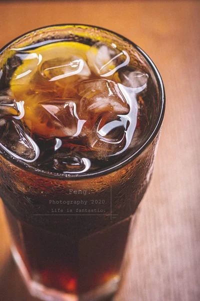 cola with ice in a glass on a wooden table