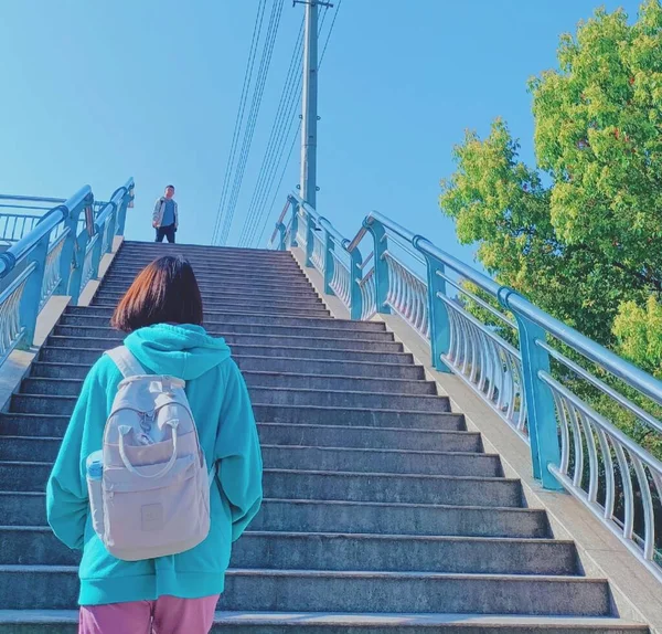 woman with backpack and stairs walking on the bridge
