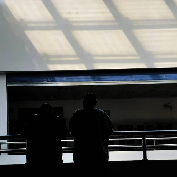 silhouette of a man in a black suit and a white shirt with a large window