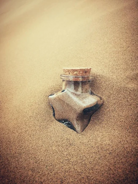 a closeup shot of a broken glass jar on a sandy beach