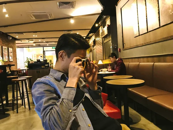 young man in a cafe with a camera